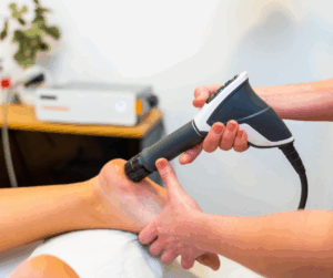 Someone performing shockwave therapy on a foot as a person is laying down