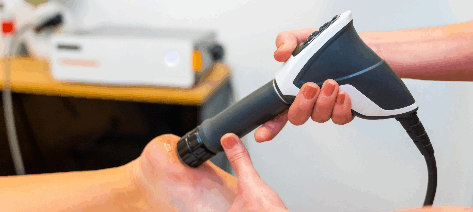 Someone performing shockwave therapy on a foot as a person is laying down